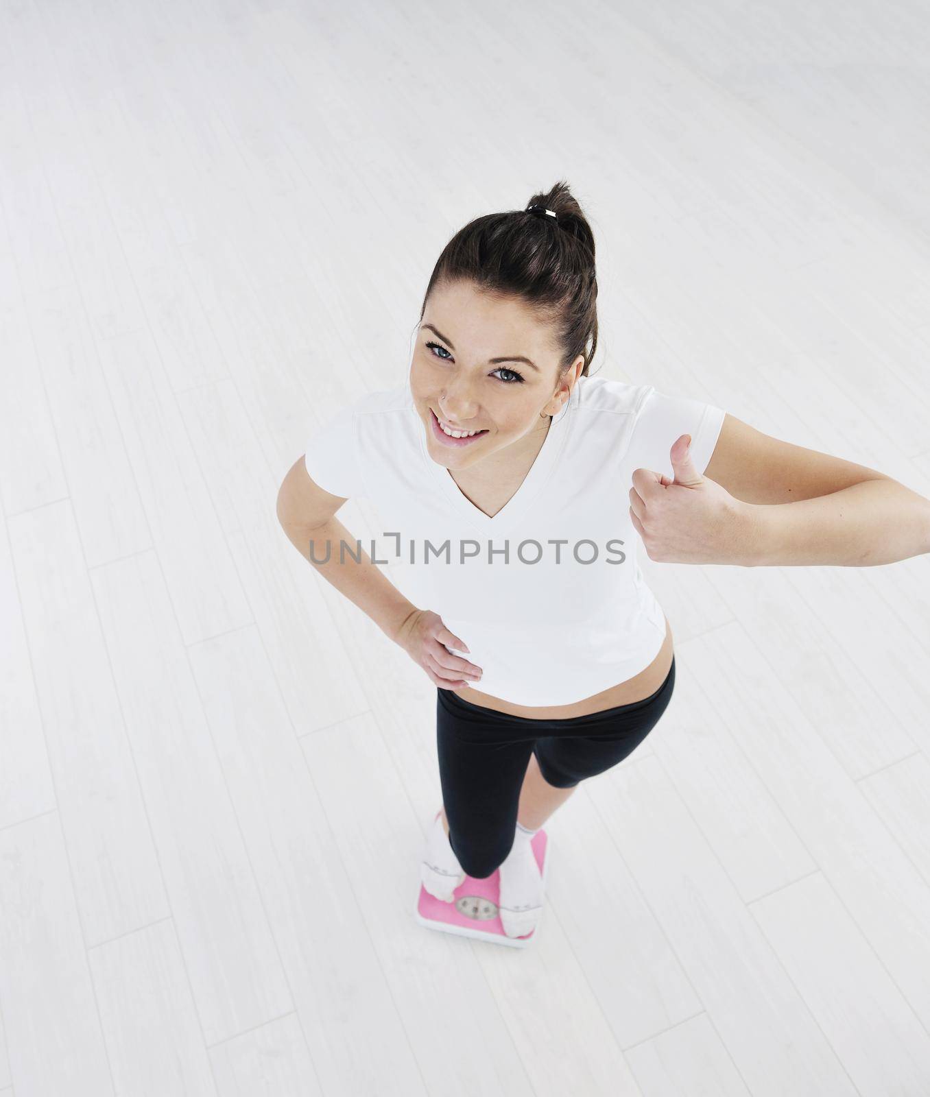 happy diet concept with young woman on pink scale at sport fitnes gym club