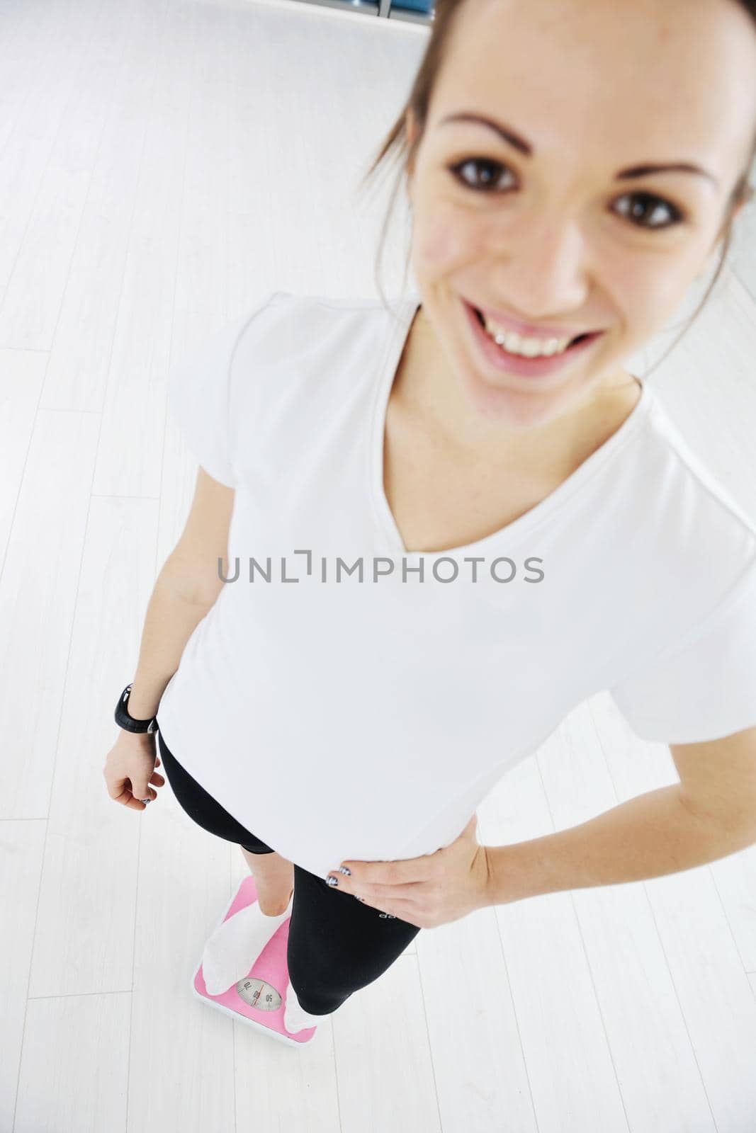 happy diet concept with young woman on pink scale by dotshock