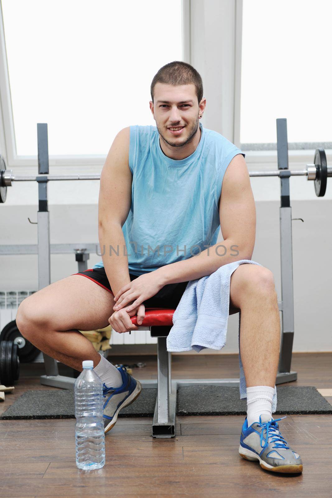young man in fintess sport club exercise withweights and relaxing