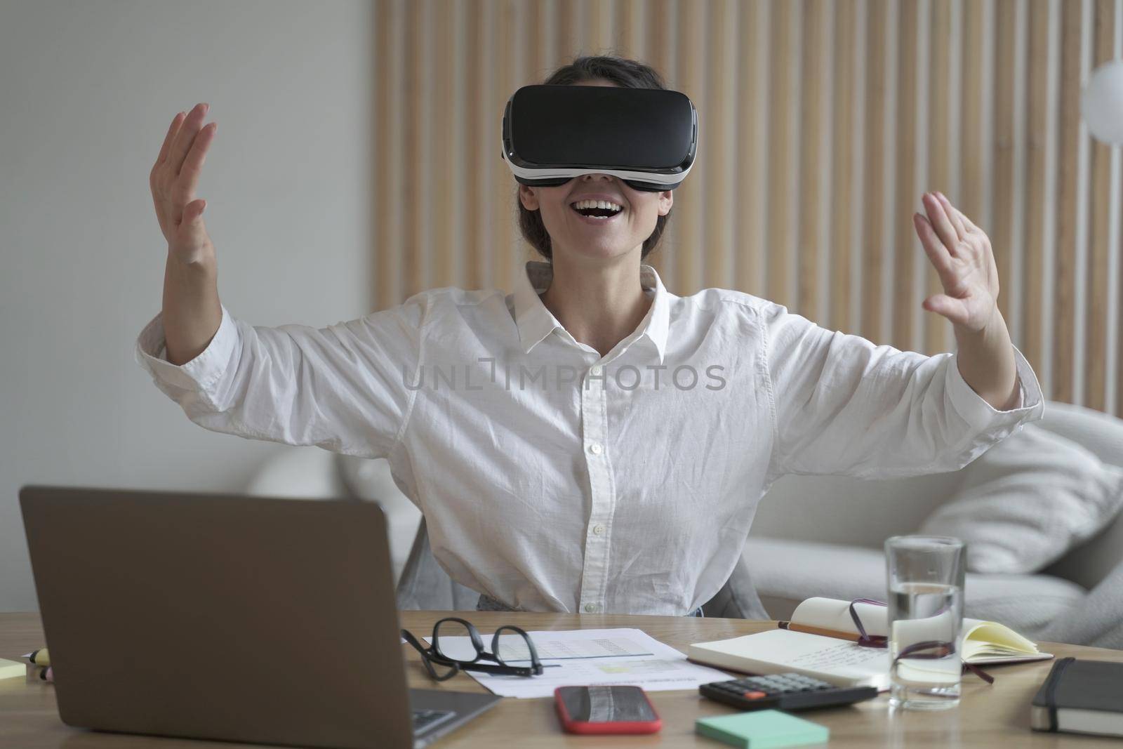 Excited european business woman testing VR glasses at work by vkstock