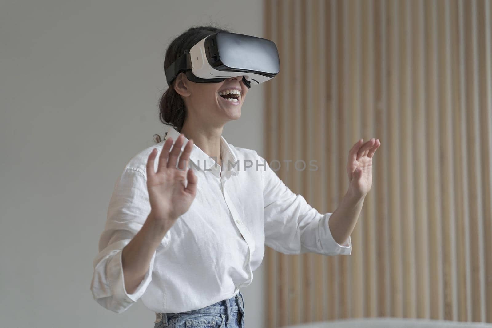 Future of job. Impressed amazed female office worker in formal outfit with opened mouth using VR glasses while working in augmented reality world, trying to touch something in air,