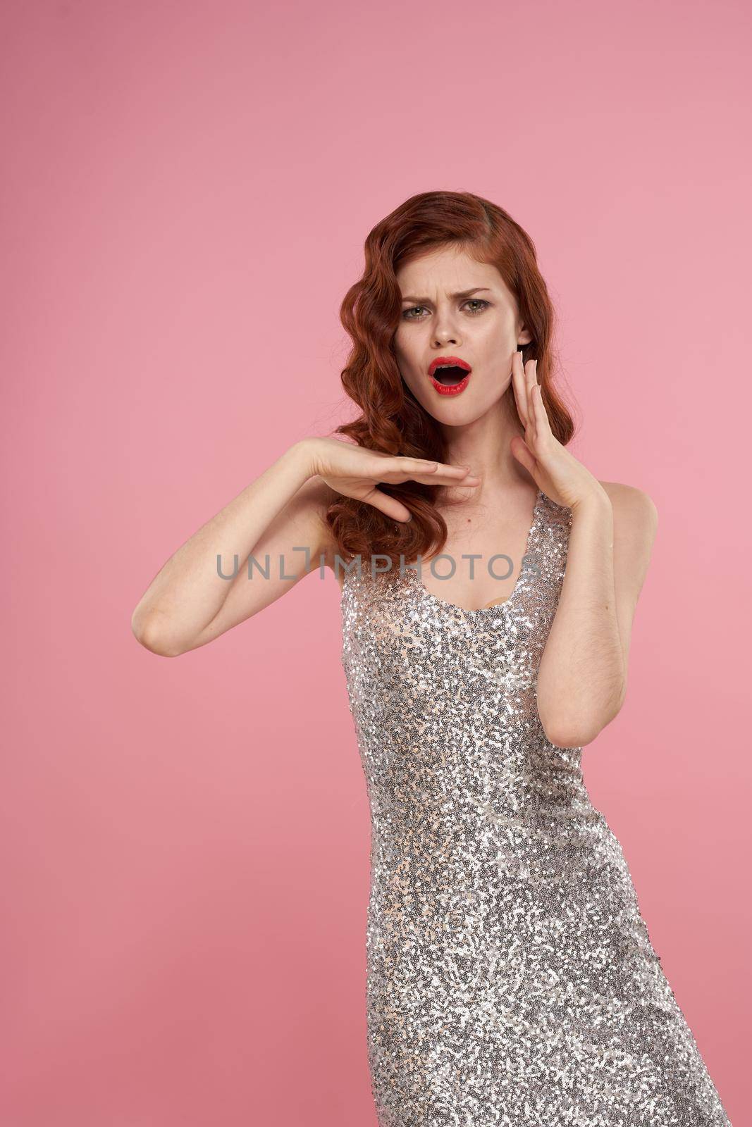 woman in a silver dress beautiful hairstyle bright makeup pink background. High quality photo
