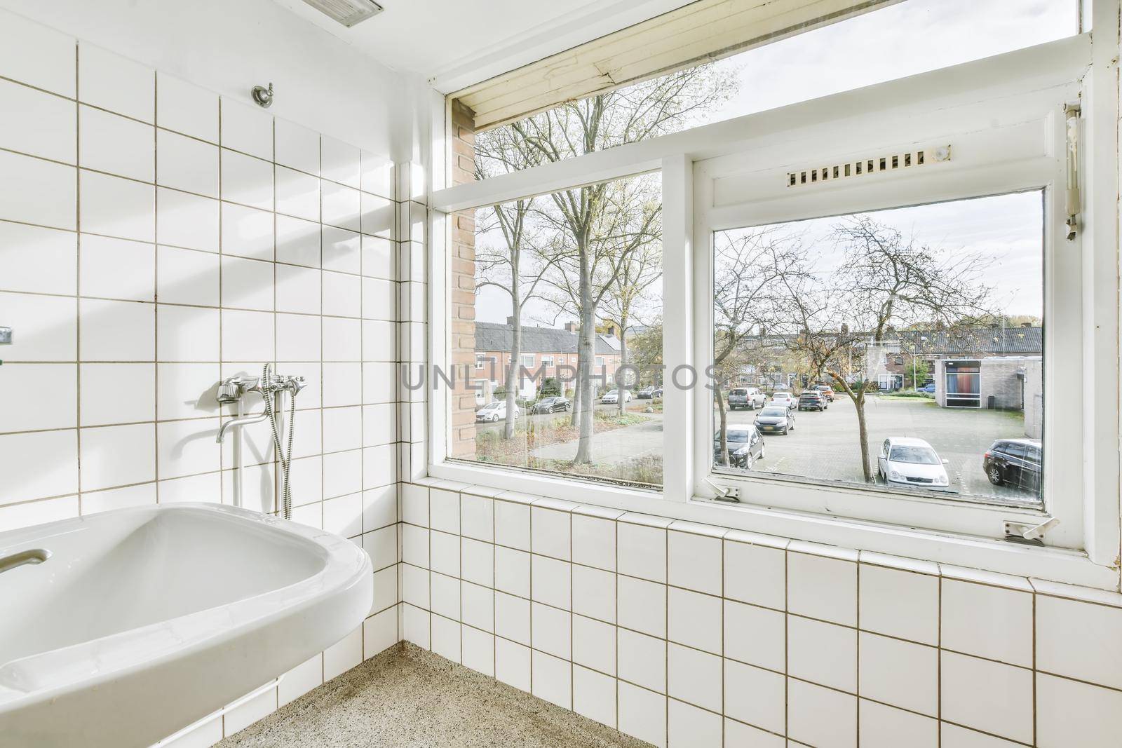 Bathroom with white tiles and a window to the street