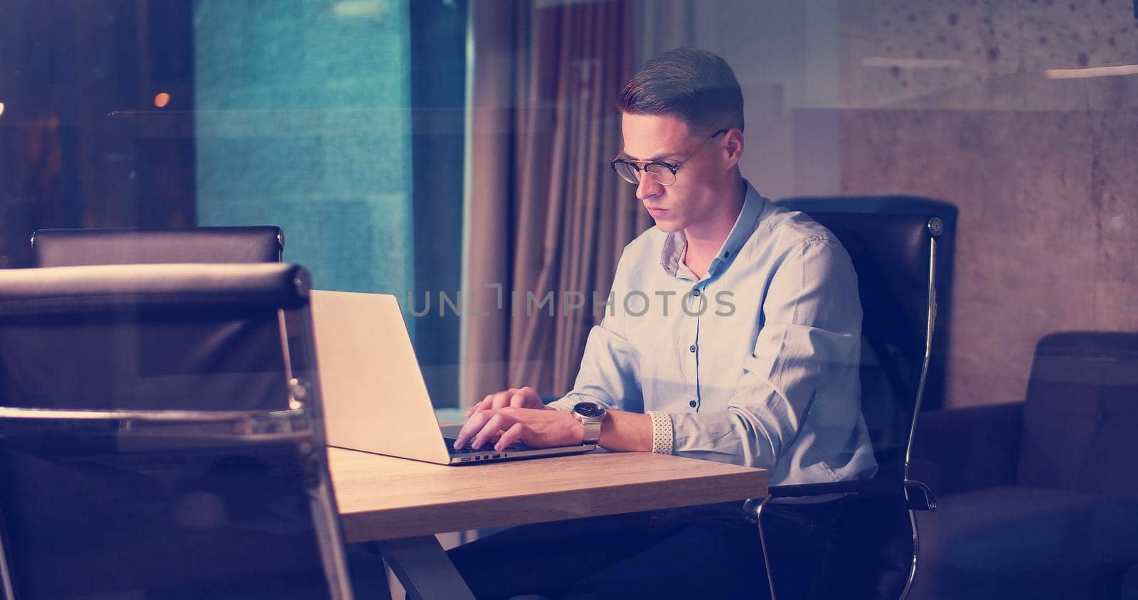 man working on laptop in dark office by dotshock