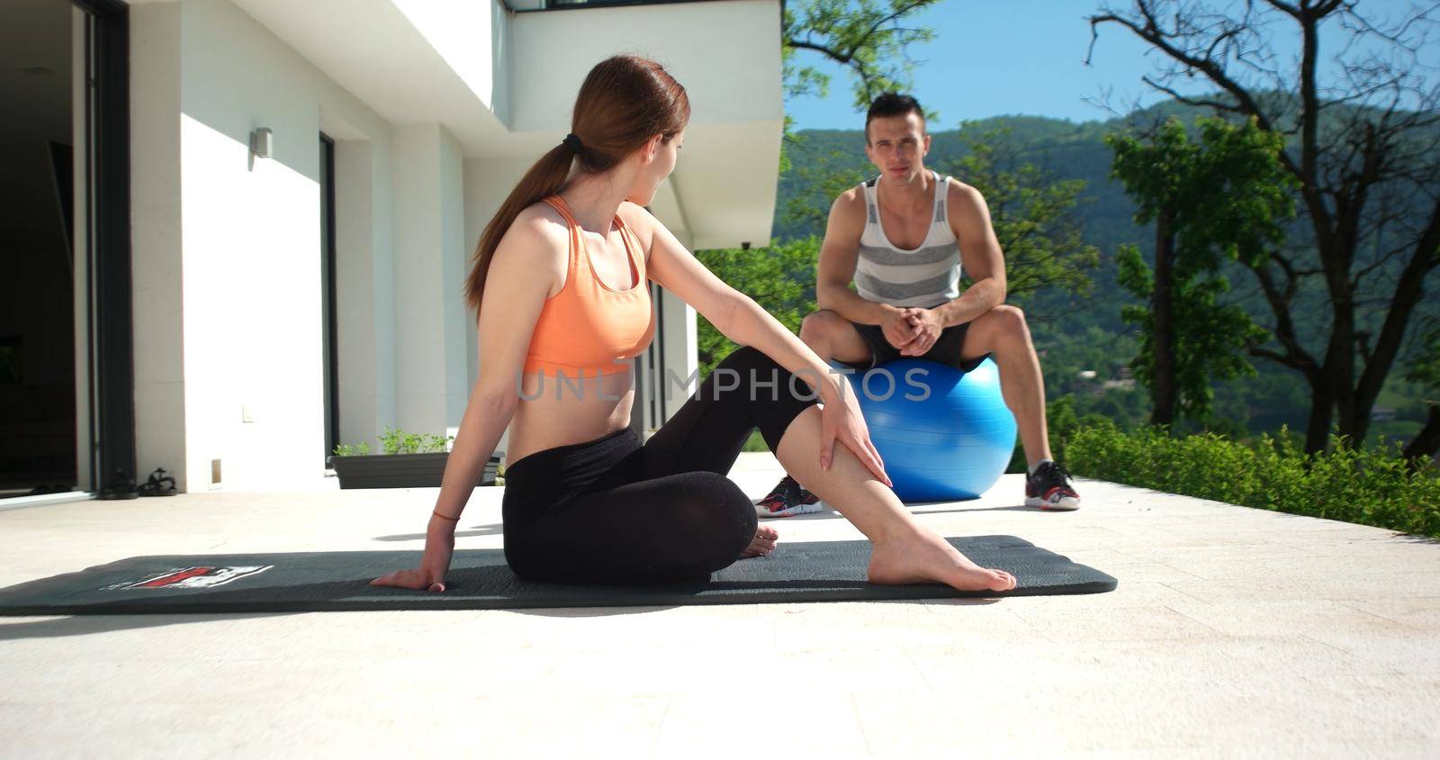 sporty couple exercising together  on terace in front of mansion