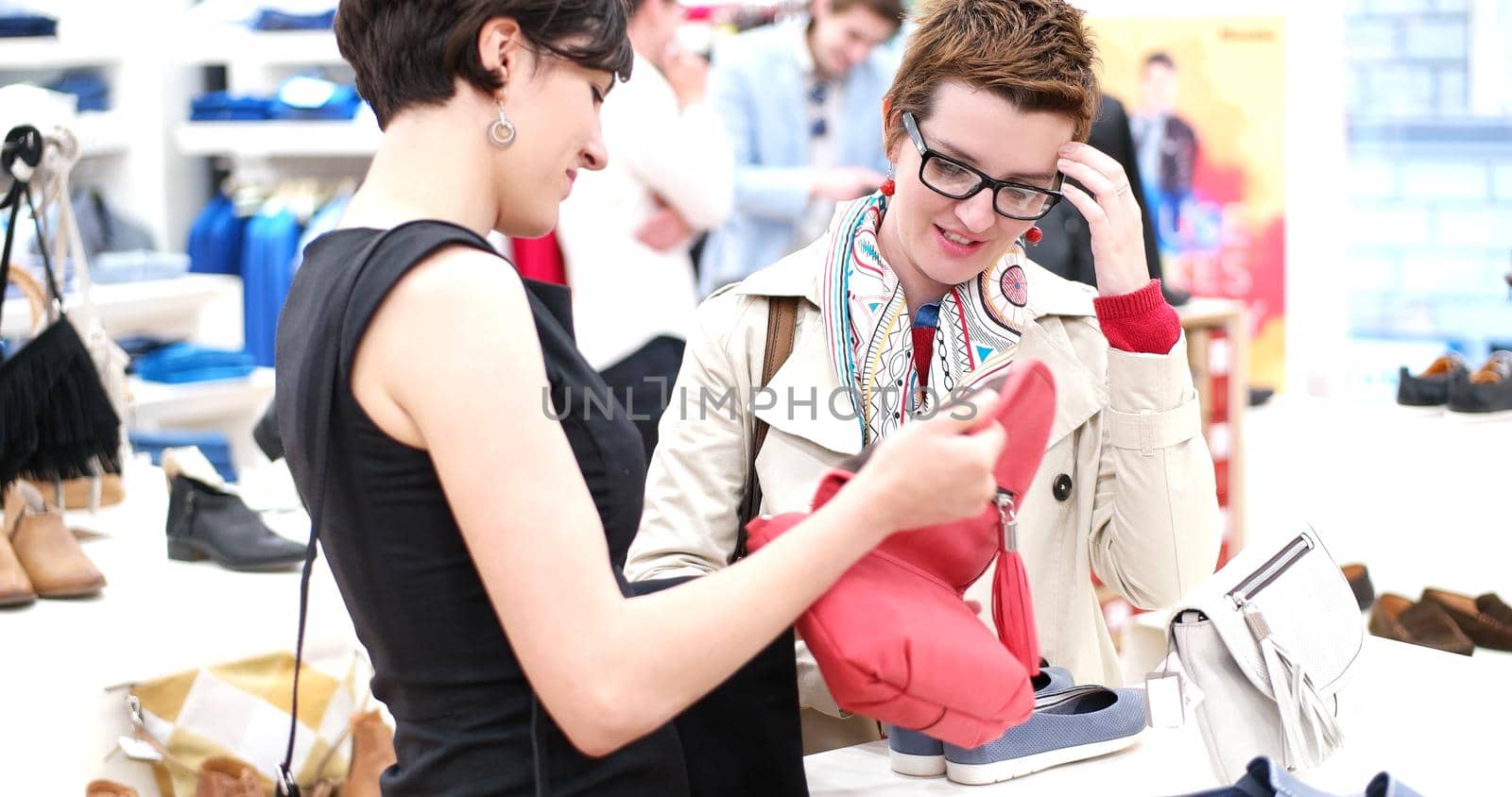 Two Girl-Friends On Shopping Walk On Shopping Centre With Bags And Choosing