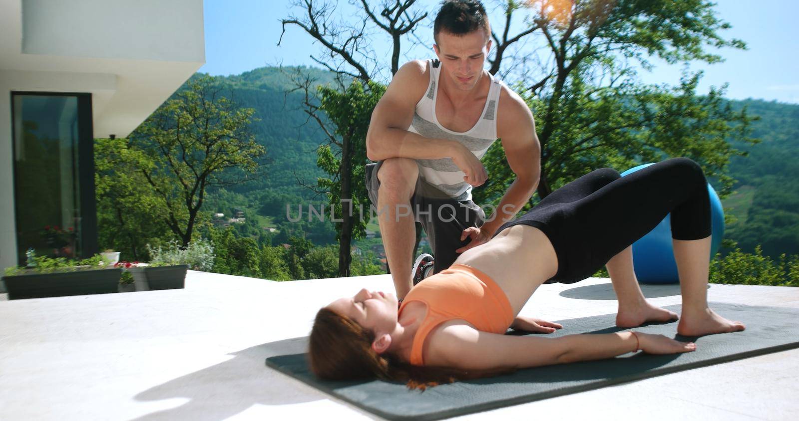 Couple Doing Stretching Exercises Together in front of luxury villa by dotshock