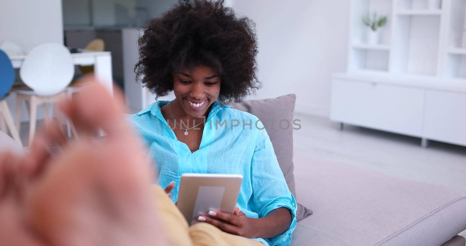 Young african american woman at home relaxing in her luxury lliving room reading a digital tablet PC surf internet and work