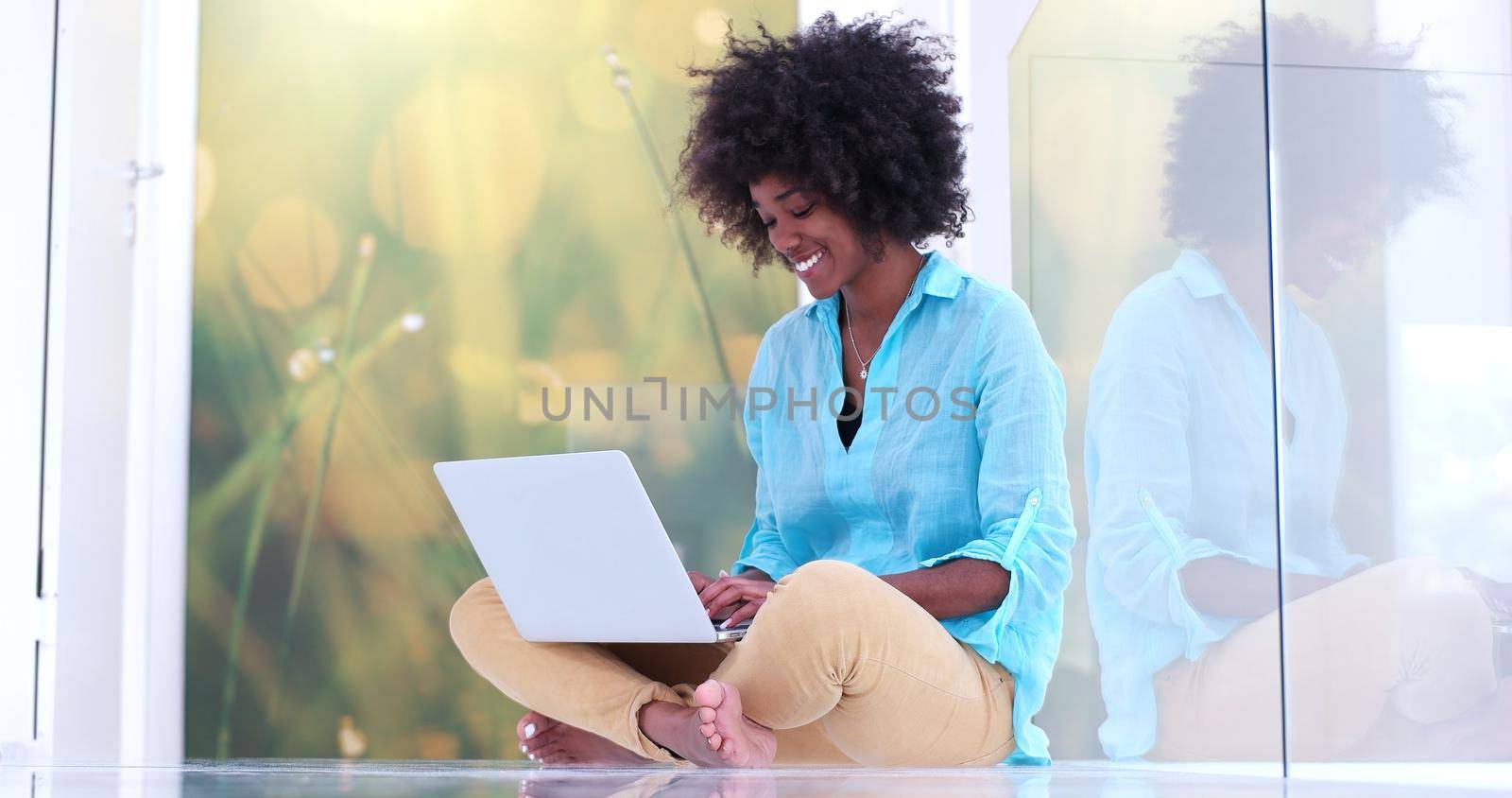 beautiful young african american women using laptop computer on the floor of her luxury home