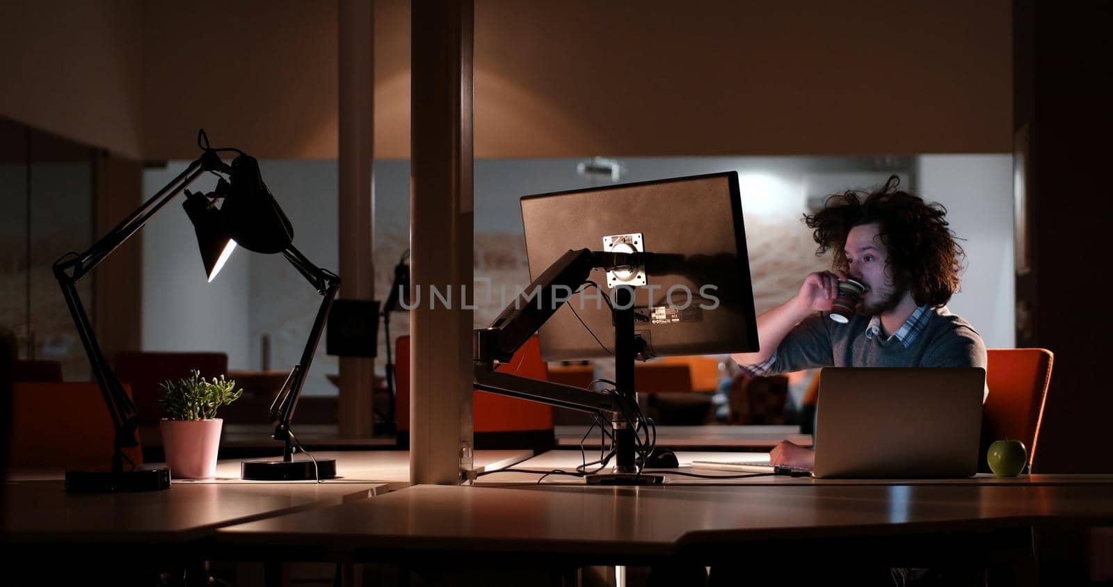 Young man working on computer at night in dark office. The designer works in the later time.