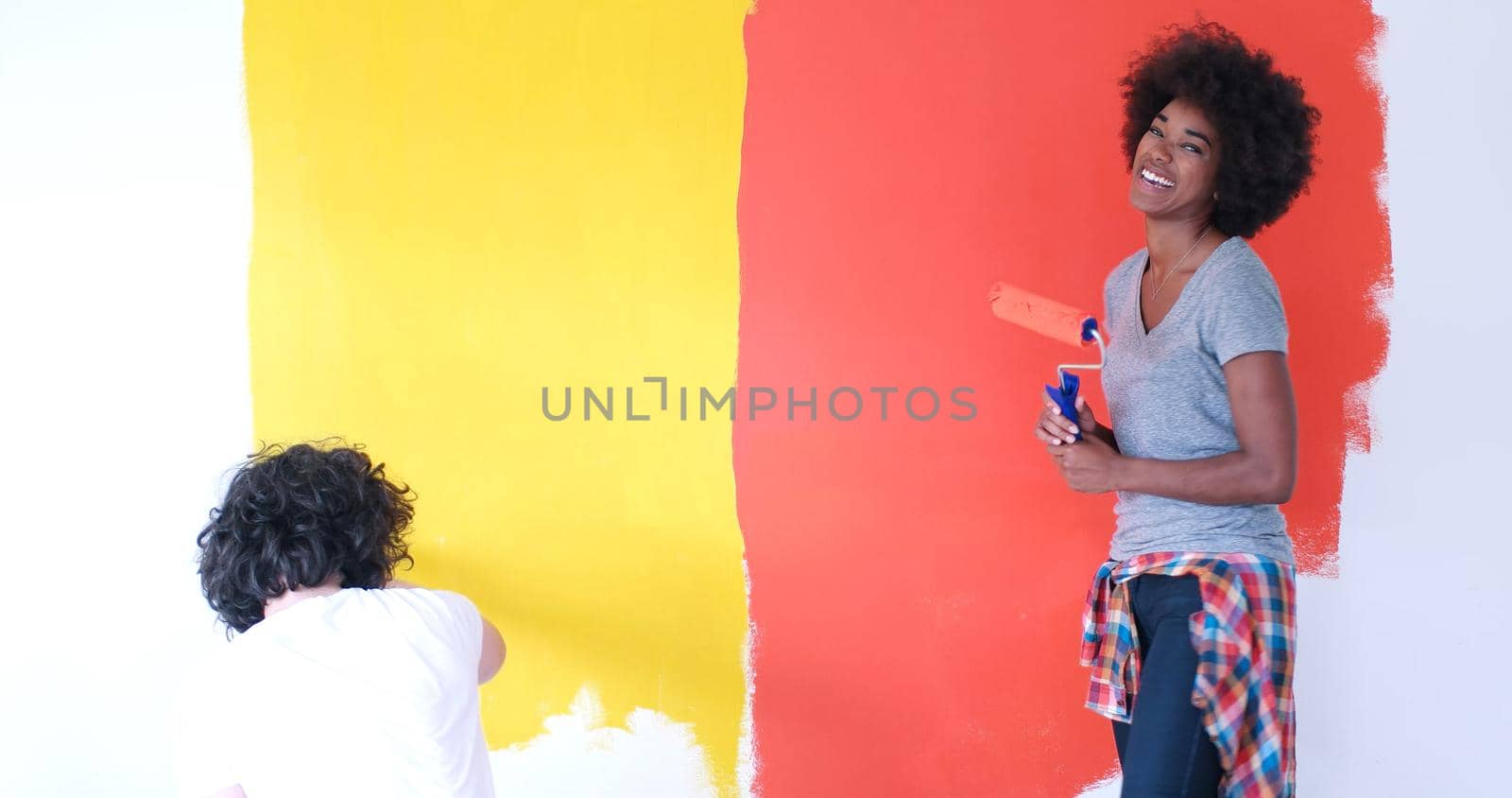 happy young multiethnic couple painting interior wall of new house