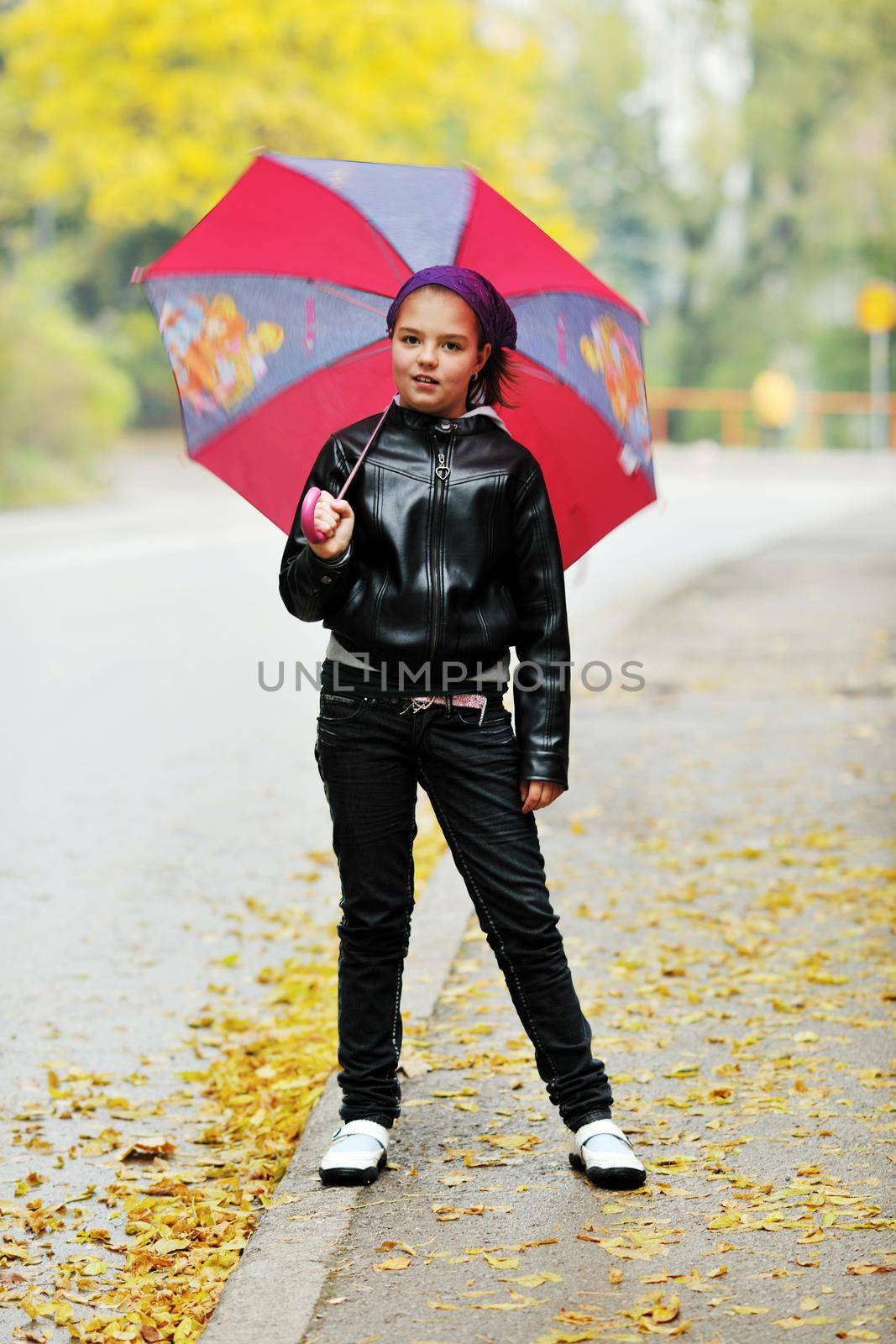 happy girl with umbrella outdoor in park on autumn season rain day