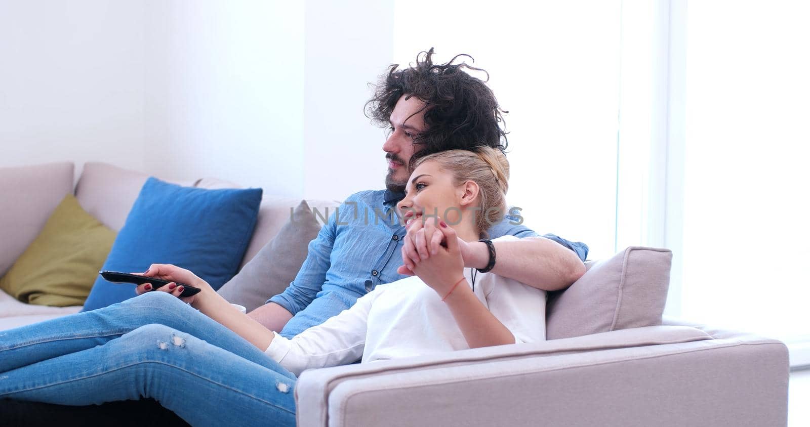 Young couple on the sofa watching television together in their luxury home