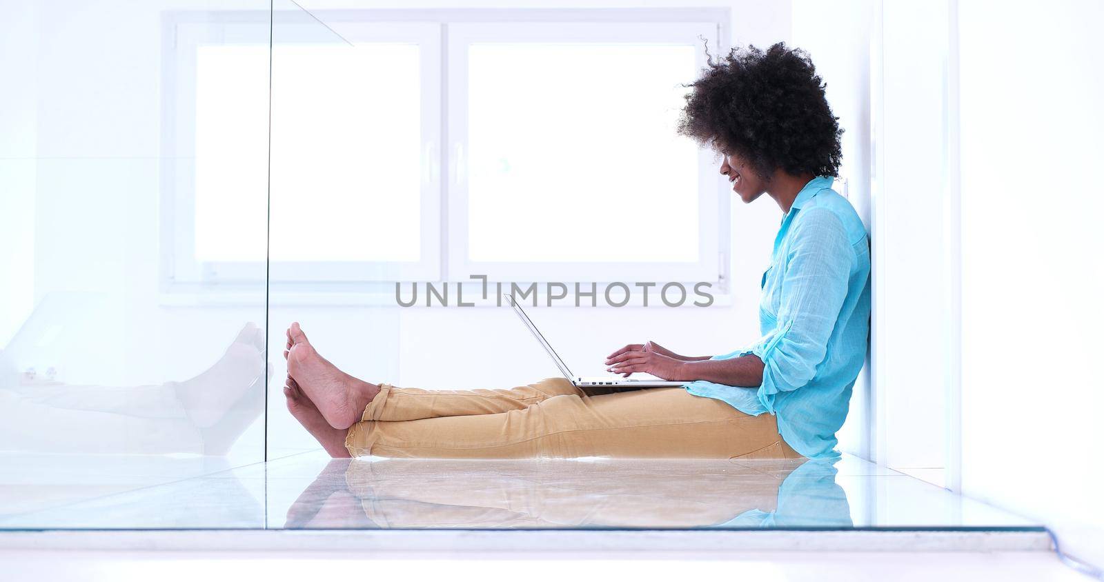 beautiful young african american women using laptop computer on the floor of her luxury home