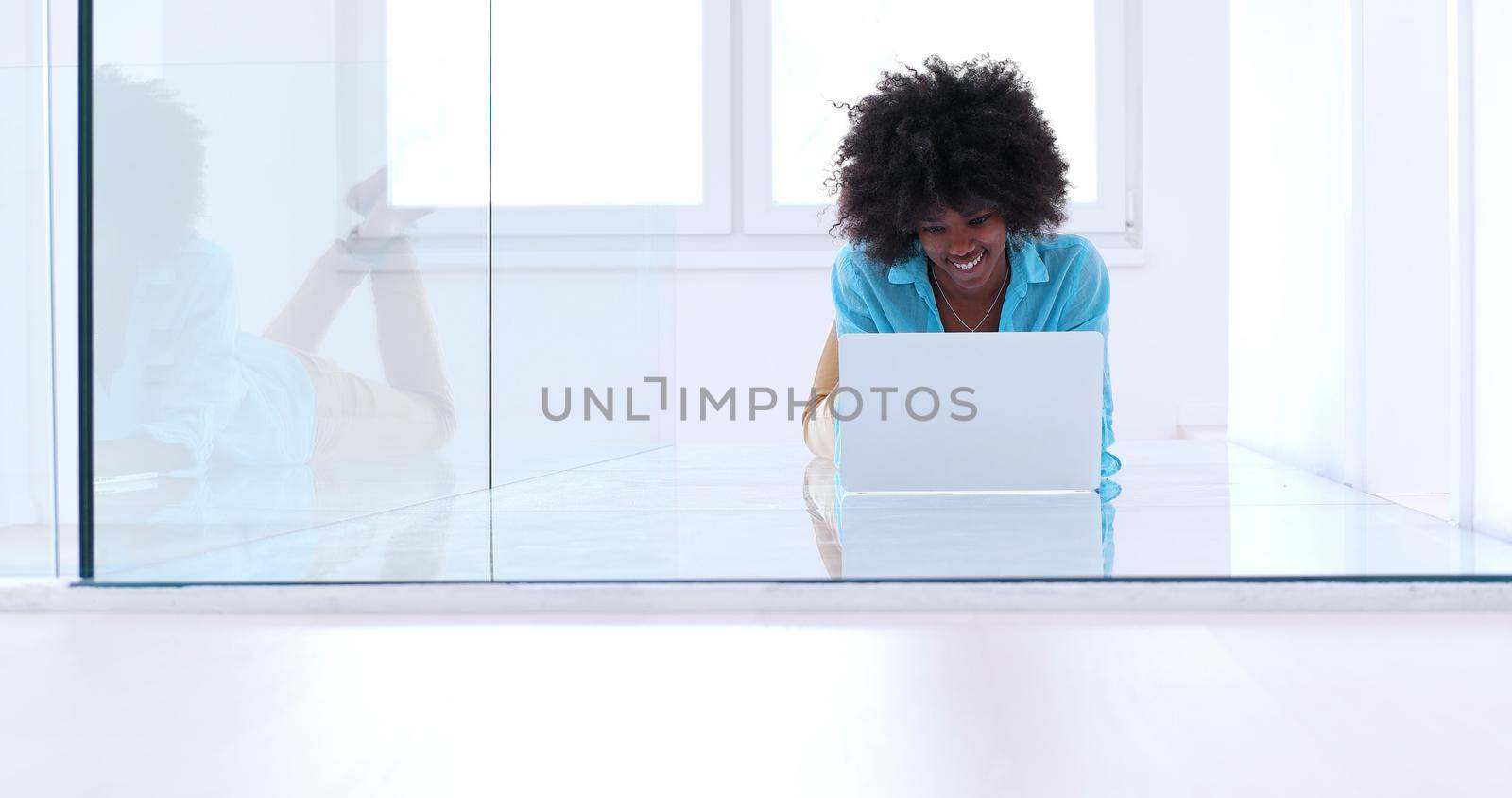 beautiful young african american women using laptop computer on the floor of her luxury home