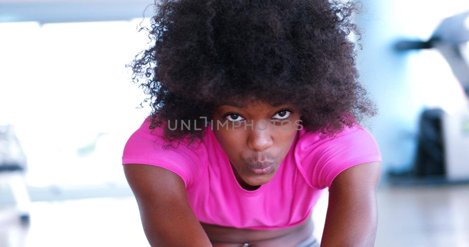 happy young african american woman in a gym stretching and warming up before workout