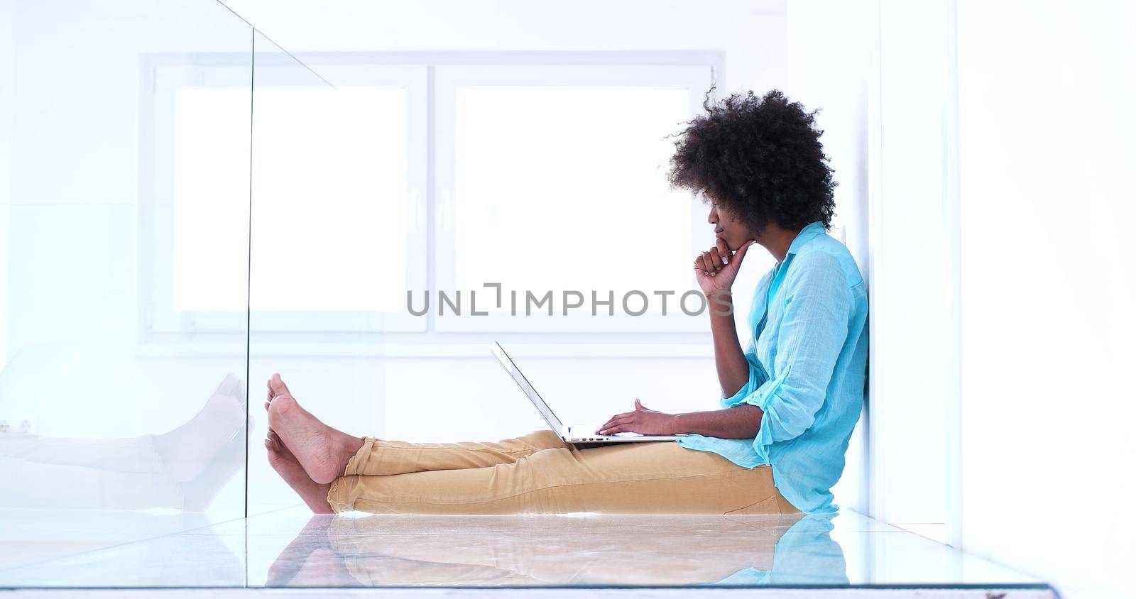 beautiful young african american women using laptop computer on the floor of her luxury home