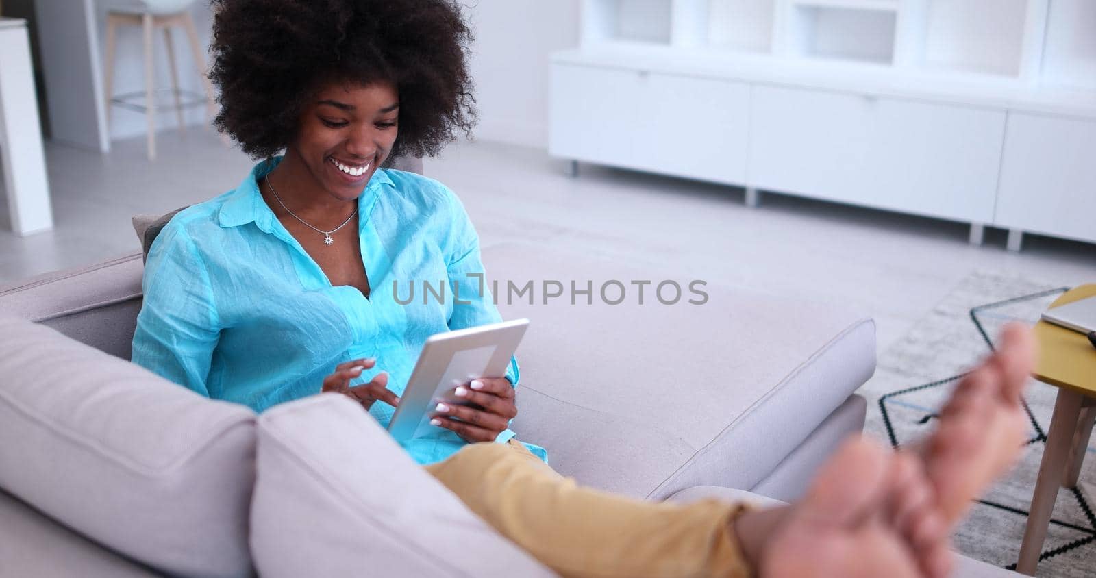 Young african american woman at home relaxing in her luxury lliving room reading a digital tablet PC surf internet and work