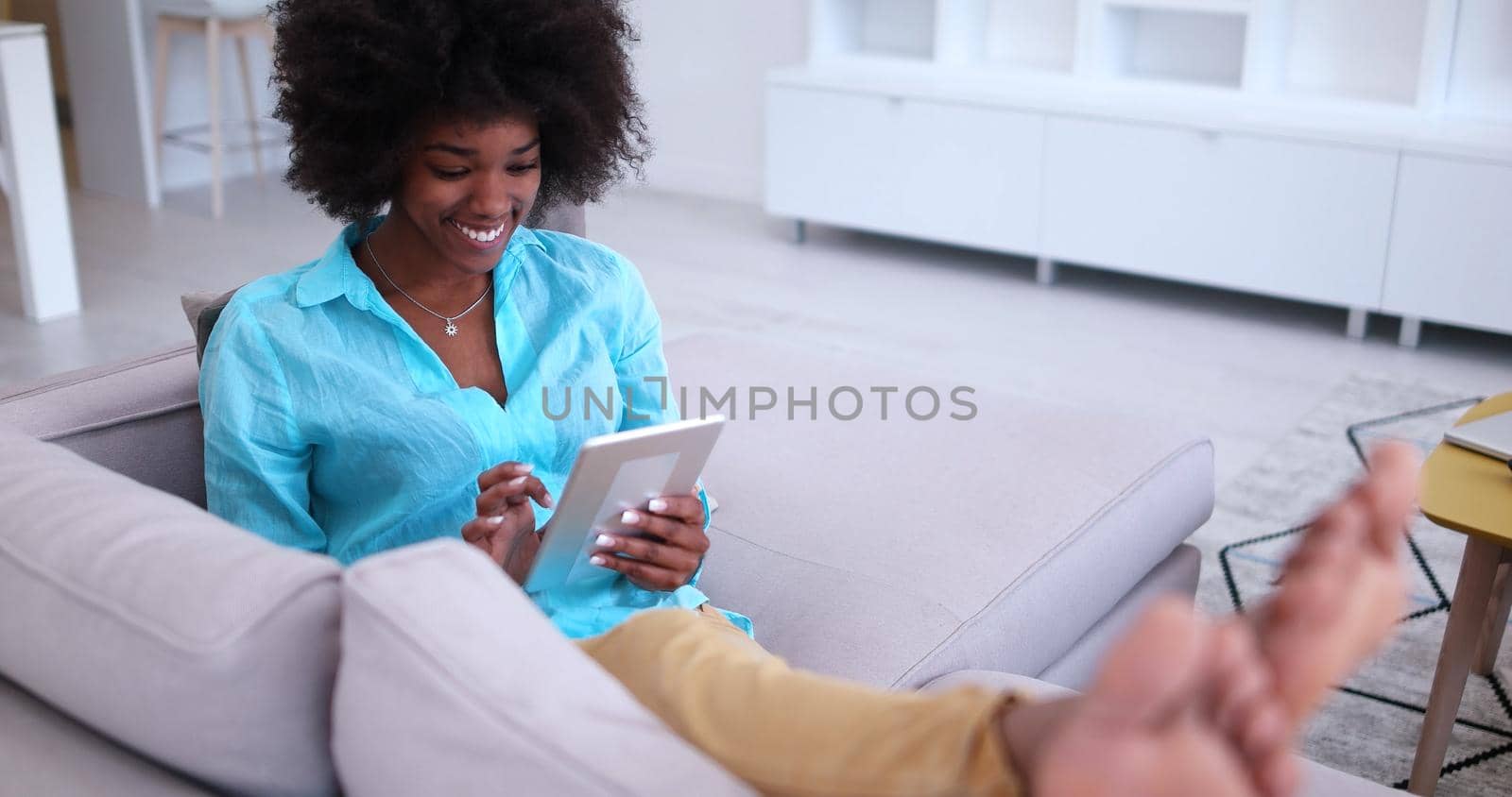 Young african american woman at home relaxing in her luxury lliving room reading a digital tablet PC surf internet and work