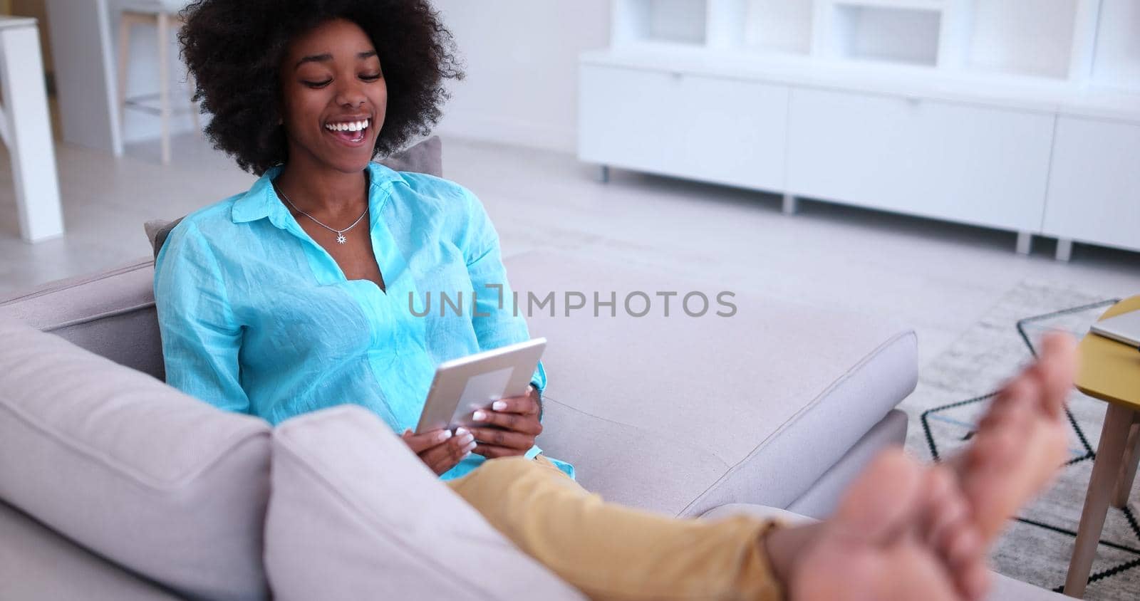 Young african american woman at home relaxing in her luxury lliving room reading a digital tablet PC surf internet and work