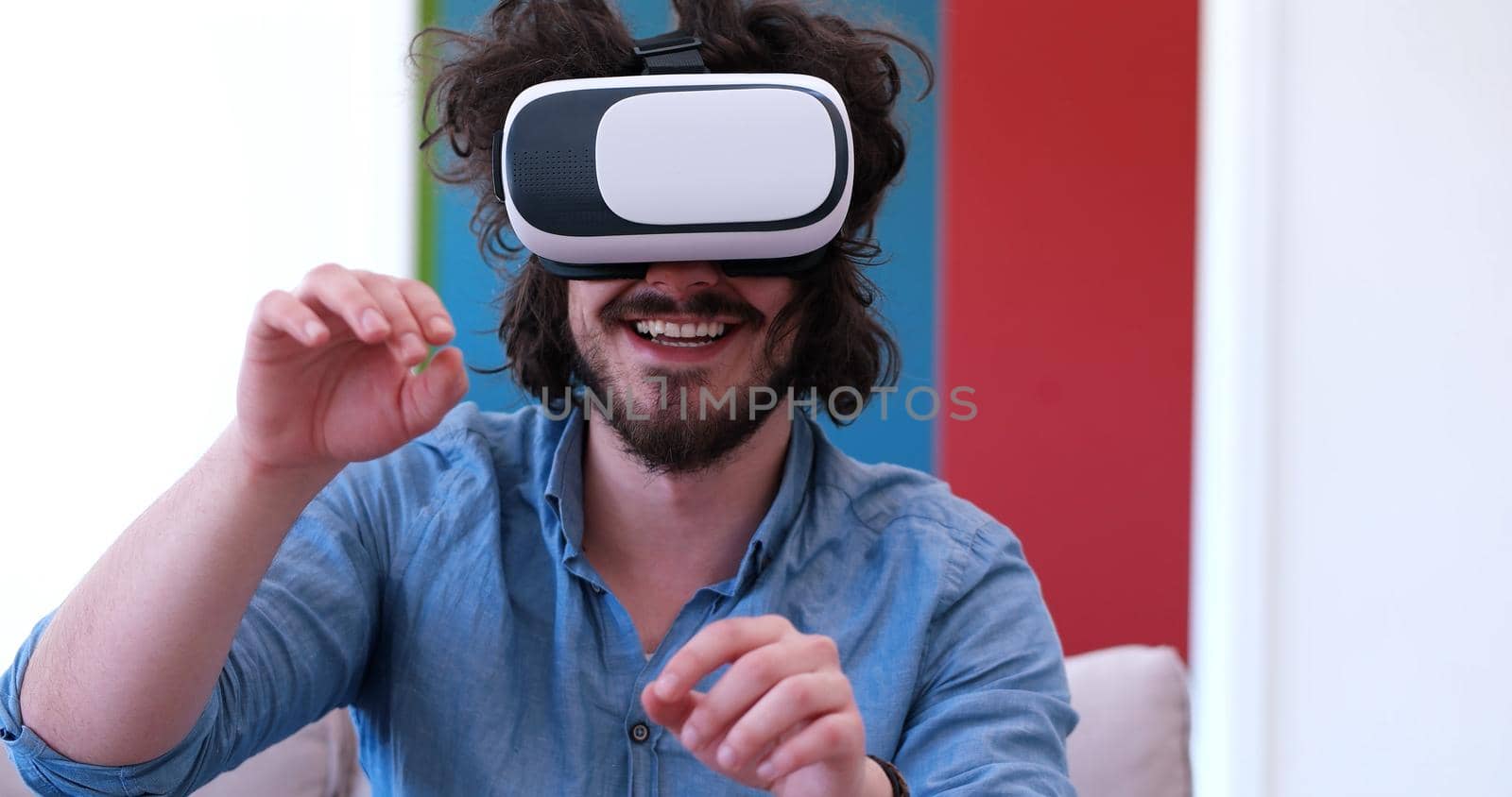 happy man getting experience using VR-headset glasses of virtual reality at home