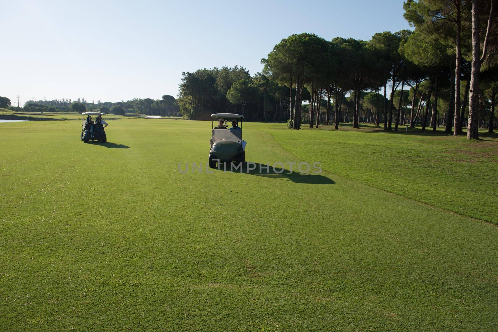 golf players driving cart at course on beautiful morning sunrise. friends together have fun and relax on vacation.