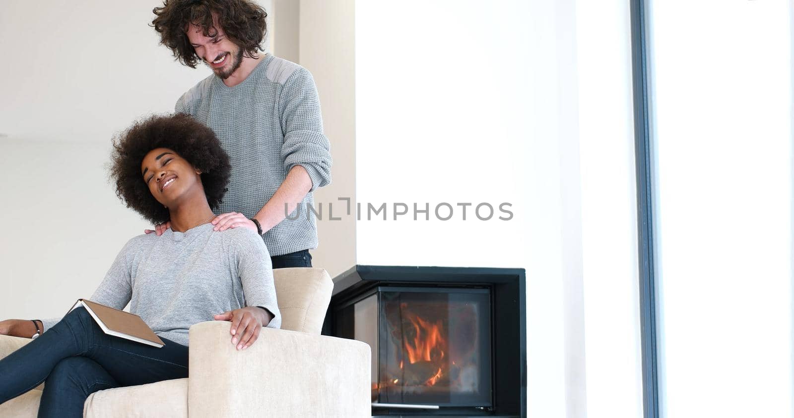 multiethnic couple hugging in front of fireplace by dotshock