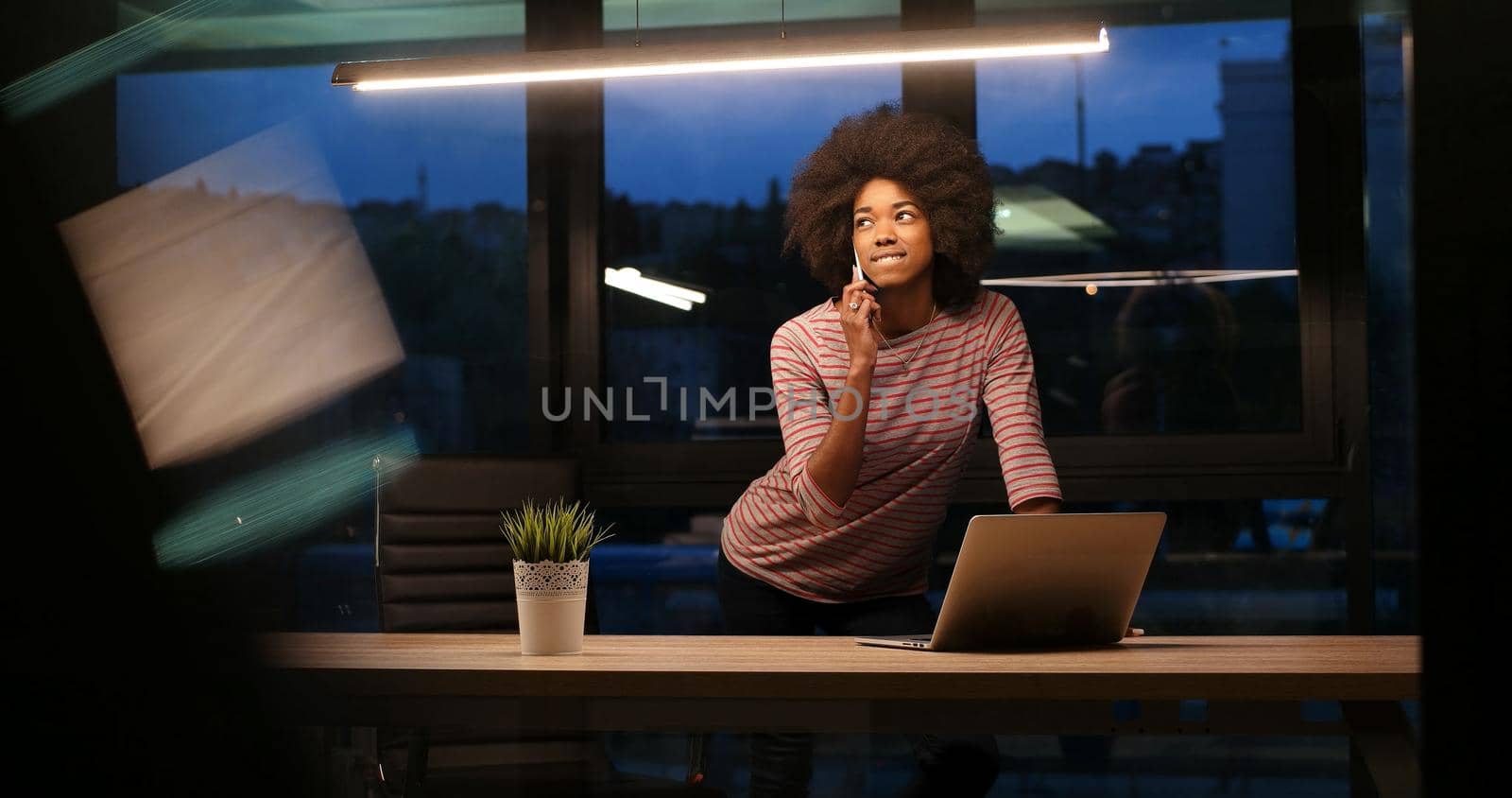 black businesswoman using a laptop in night startup office by dotshock