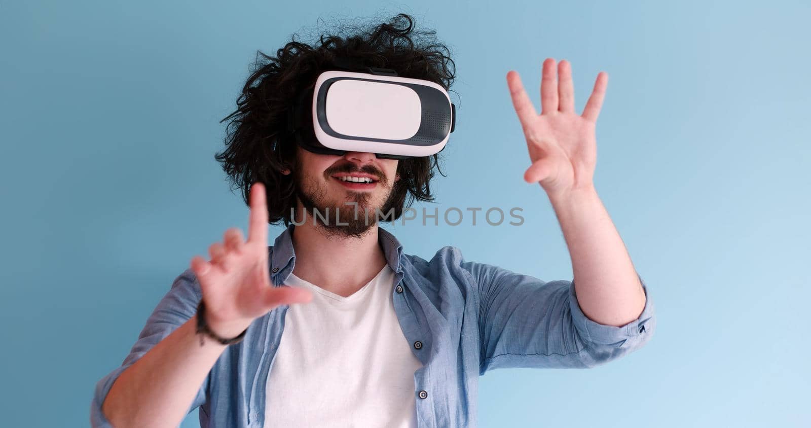 Happy man getting experience using VR headset glasses of virtual reality, isolated on blue background