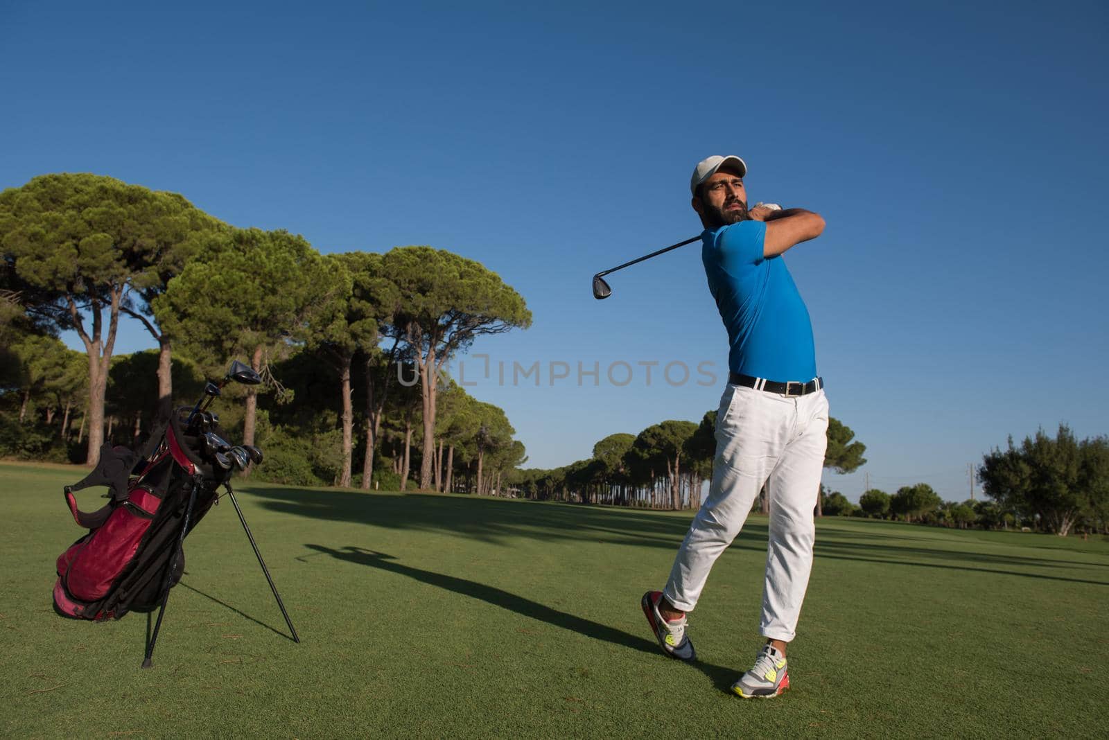 golf player hitting shot with driver on course at beautiful sunny day