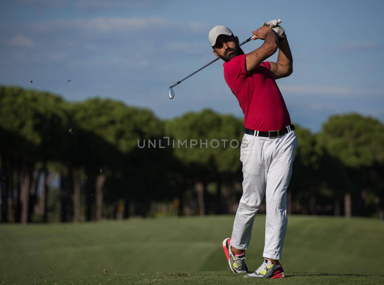 golf player hitting shot with driver on course at beautiful sunny day