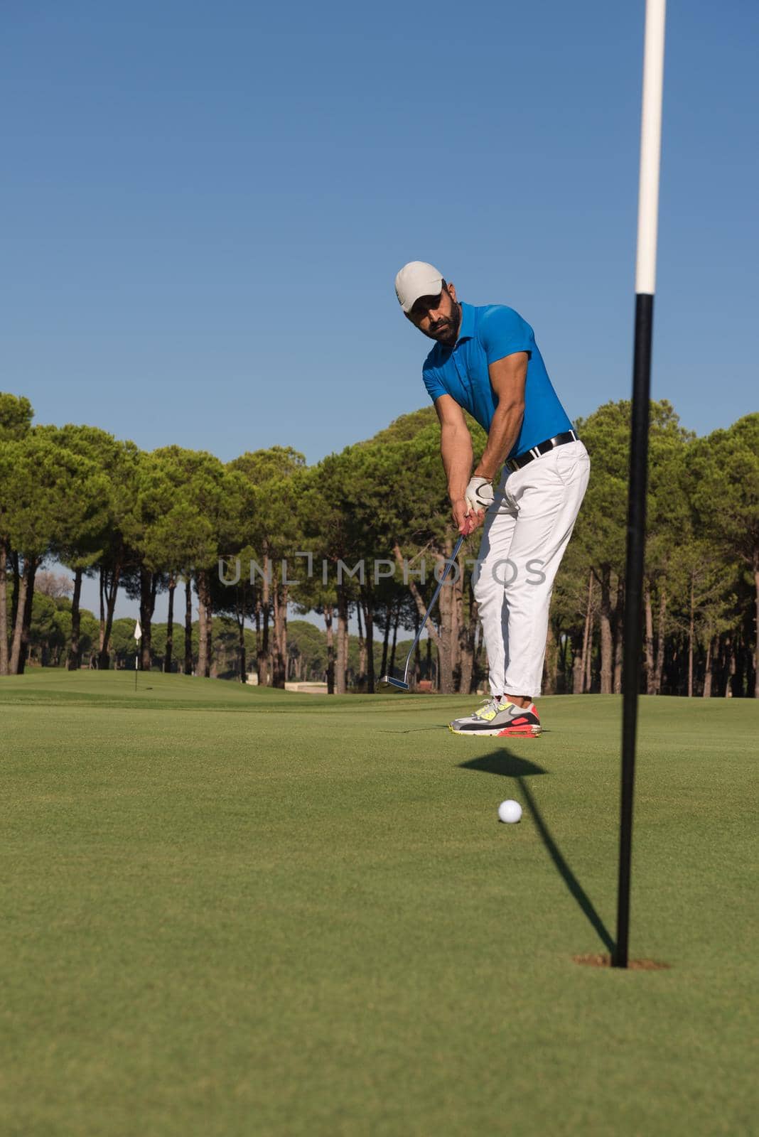 golf player hitting shot with driver on course at beautiful sunny day