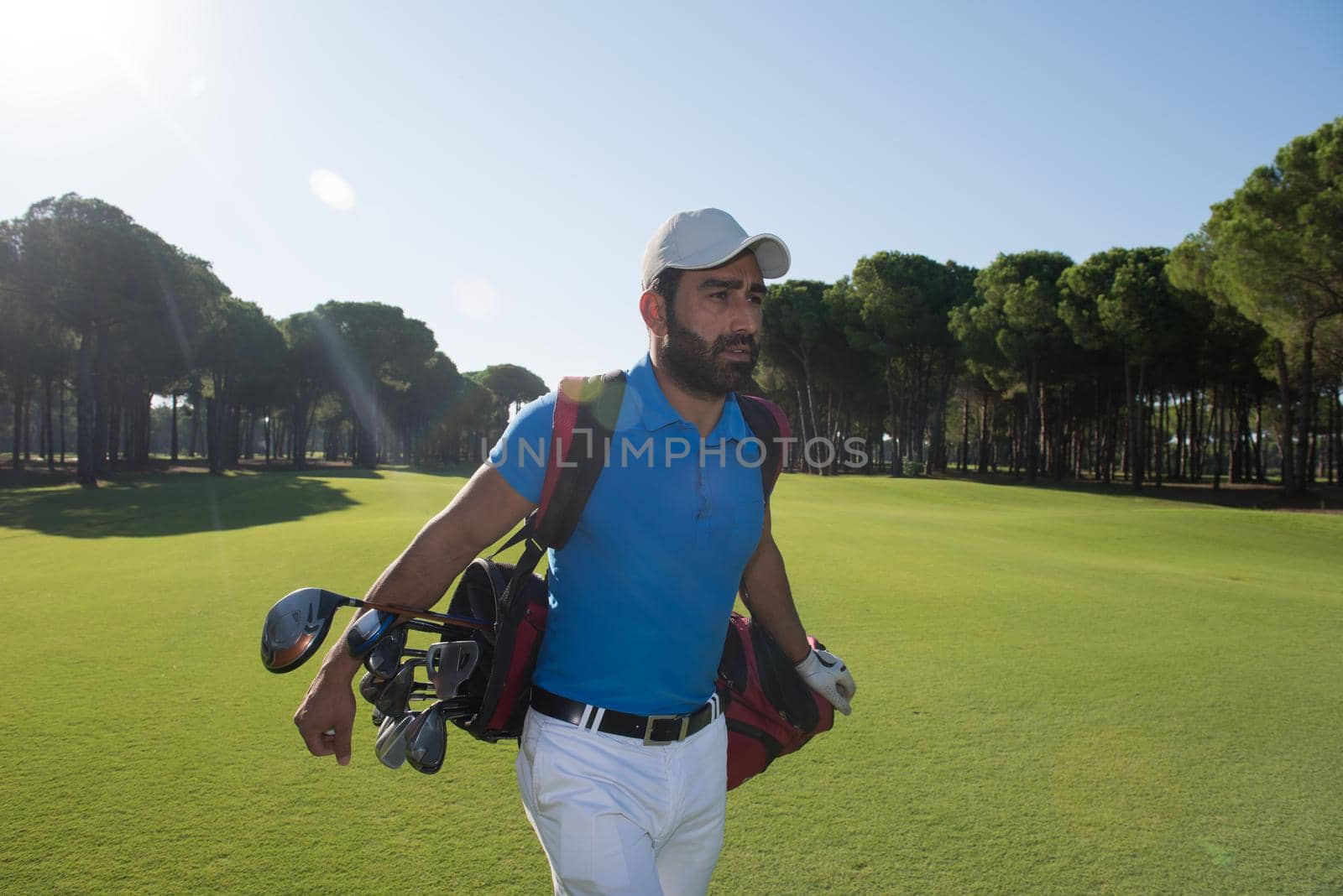 handsome middle eastern golf player carrying and bag  and walking at course on beautiful morning sunrise