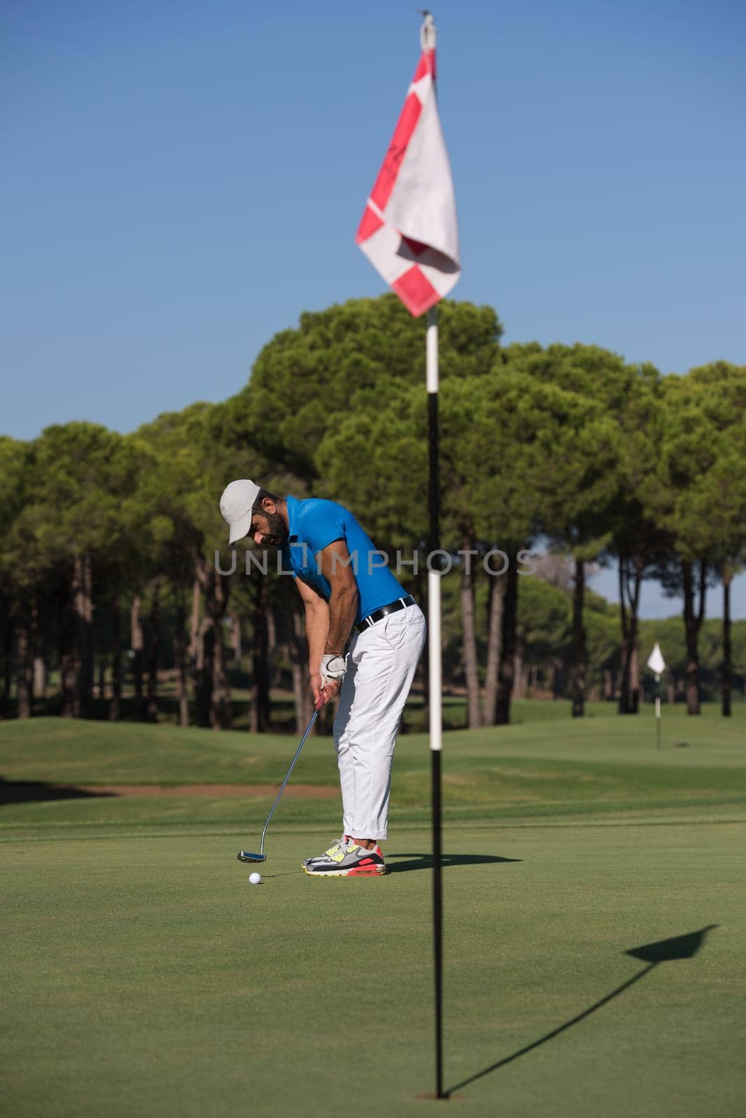 golf player hitting shot with driver on course at beautiful sunny day