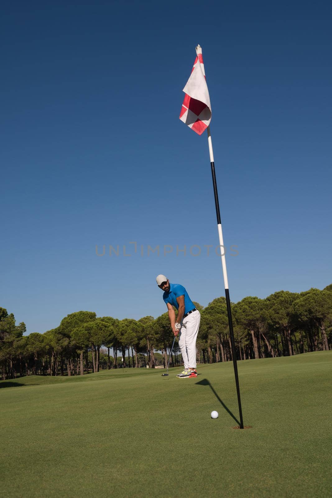 golf player hitting shot with driver on course at beautiful sunny day