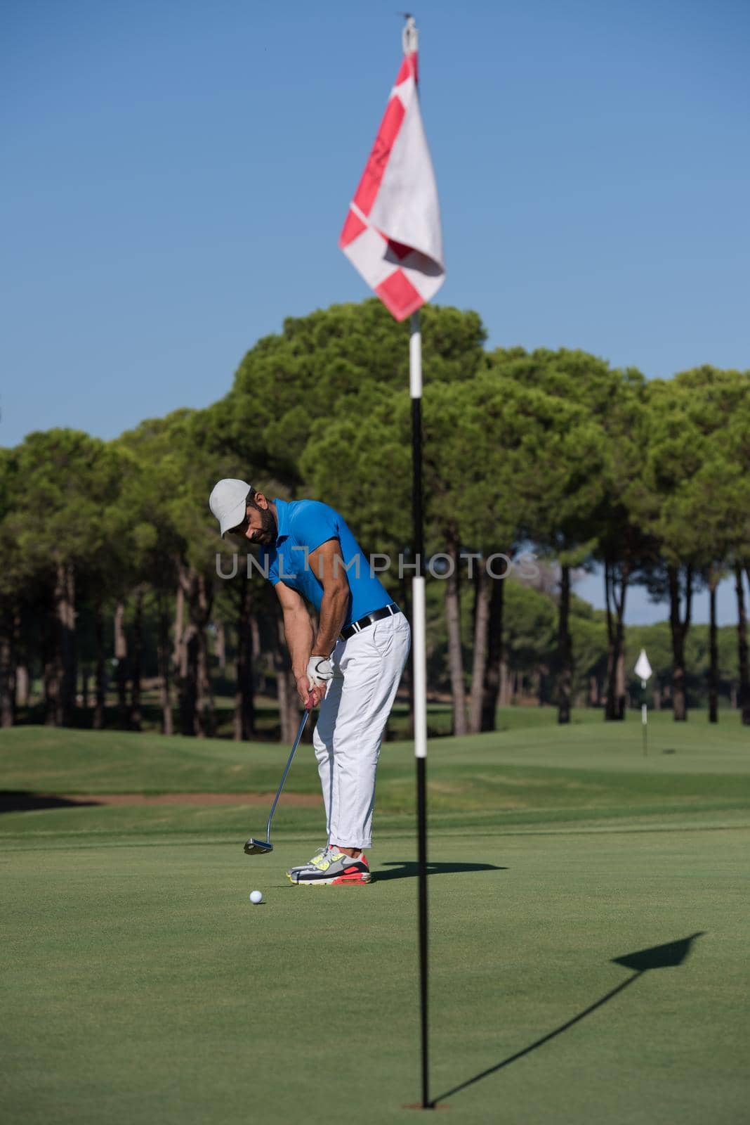 golf player hitting shot with driver on course at beautiful sunny day