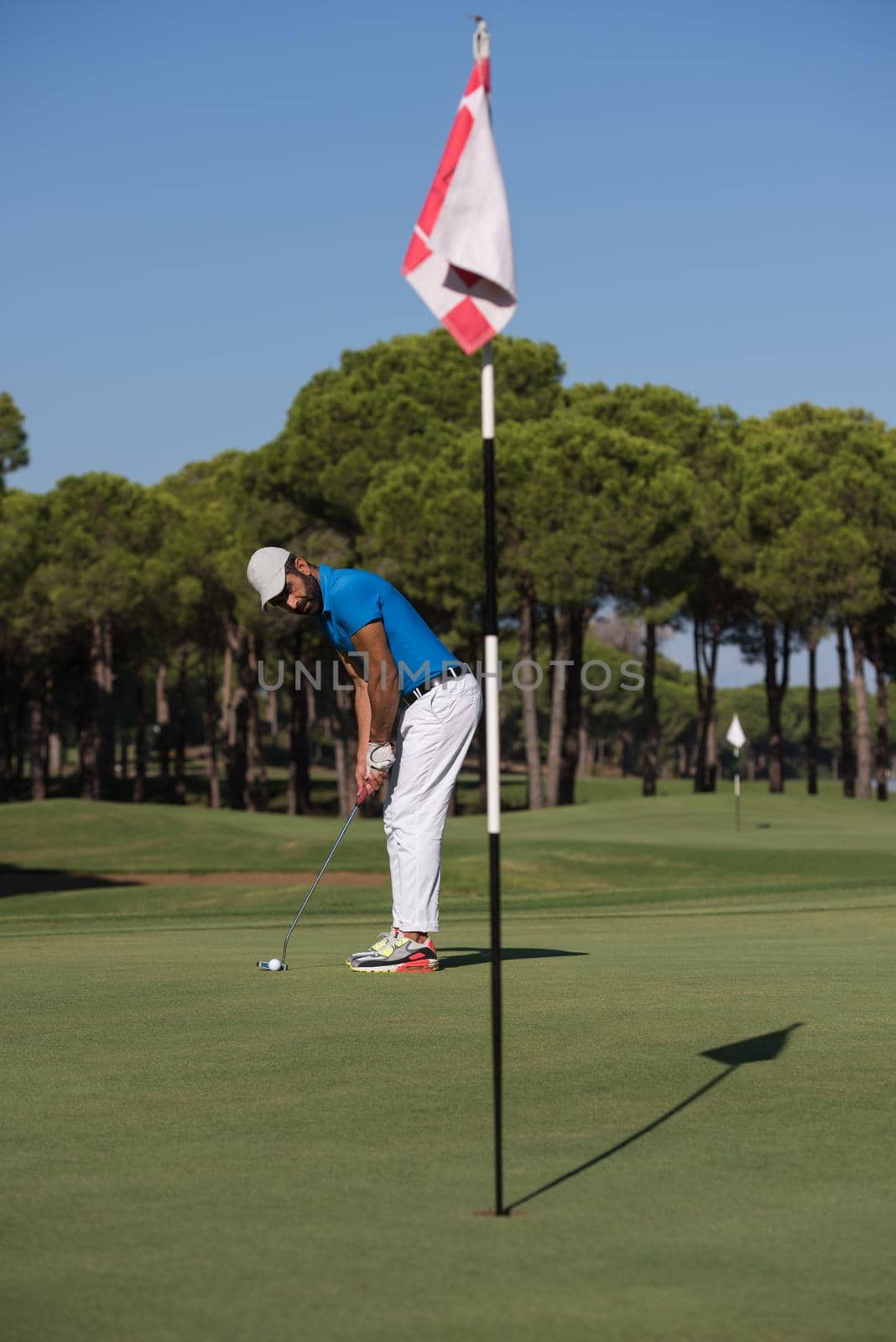 golf player hitting shot with driver on course at beautiful sunny day