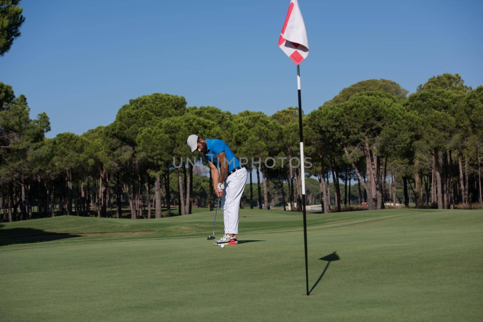 golf player hitting shot with driver on course at beautiful sunny day