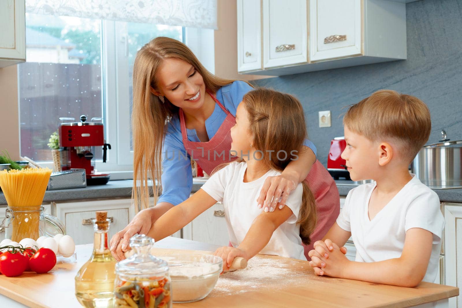 Mother and her little kids, boy and girl, helping her to prepare dough by Fabrikasimf