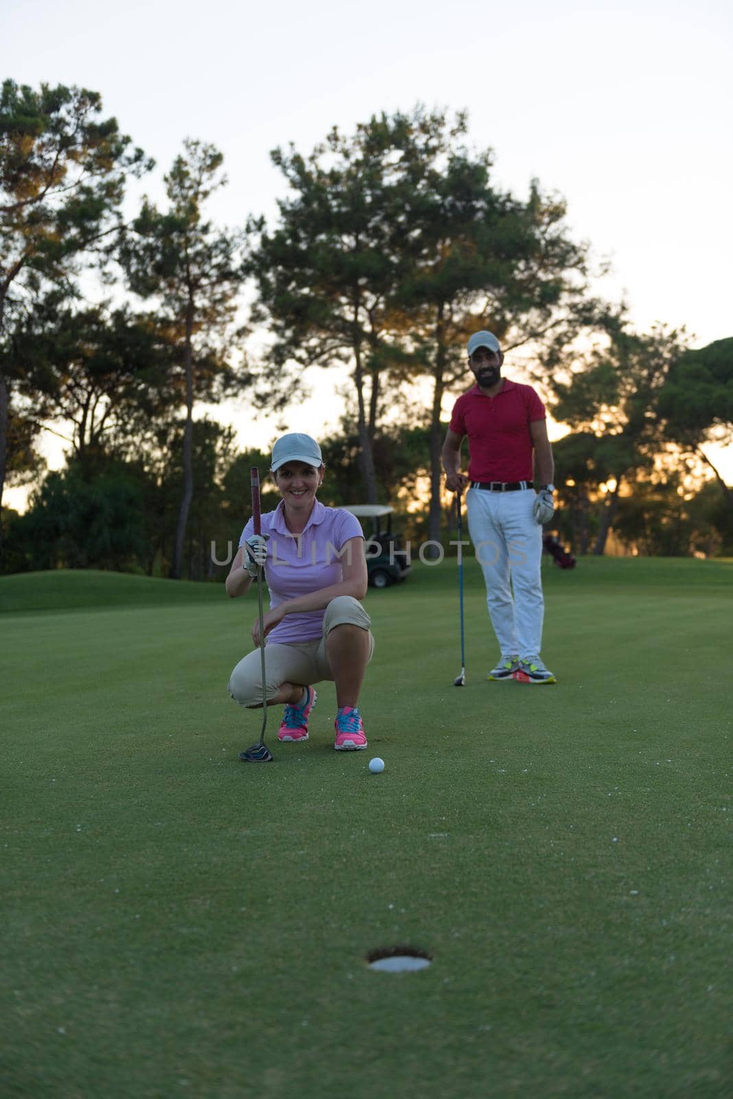 portrait of happy young  couple on golf course with beautiful sunset in background