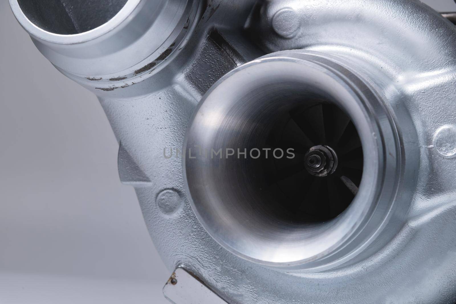 Close-up of an auto part for an internal combustion engine. Gas turbine. Turbo supercharger new on a gray background. Parts background.