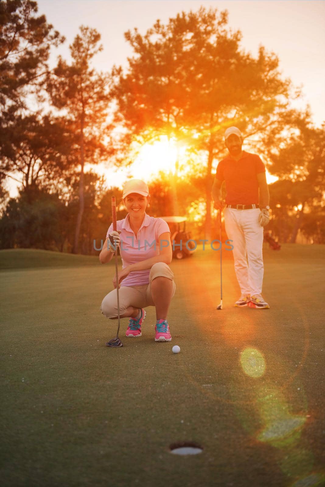 portrait of happy young  couple on golf course with beautiful sunset in background