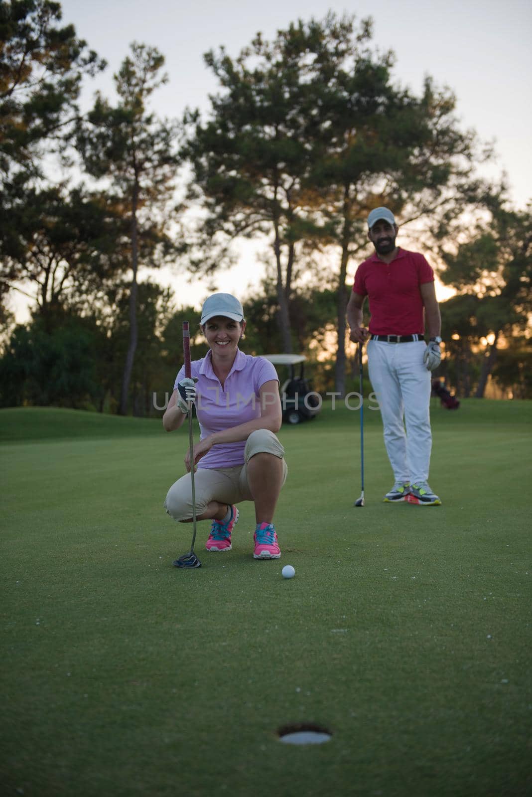 portrait of happy young  couple on golf course with beautiful sunset in background