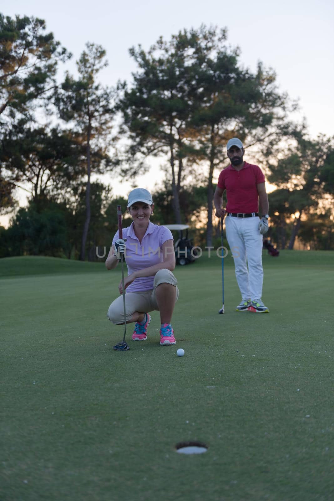 portrait of happy young  couple on golf course with beautiful sunset in background