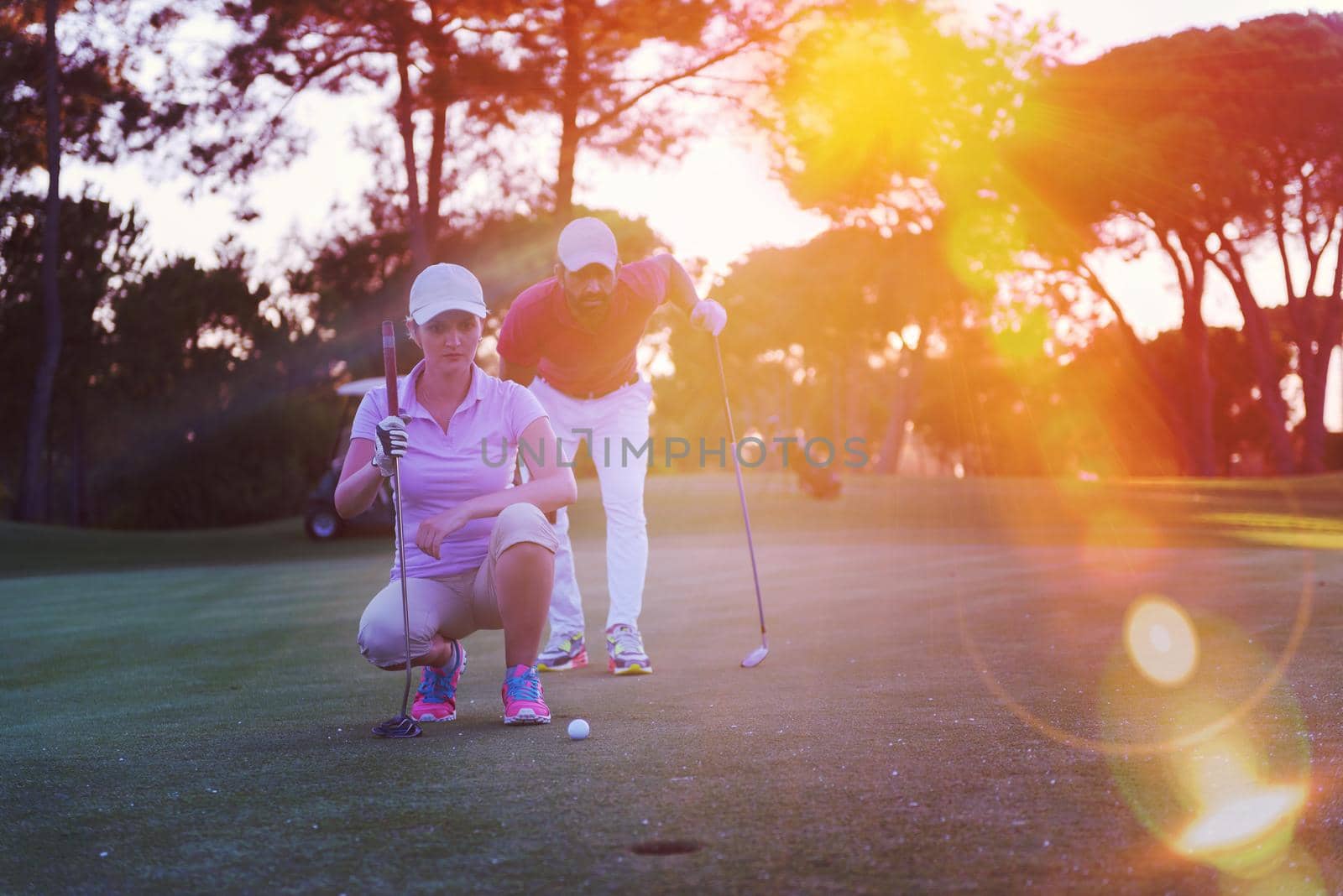 portrait of happy young  couple on golf course with beautiful sunset in background