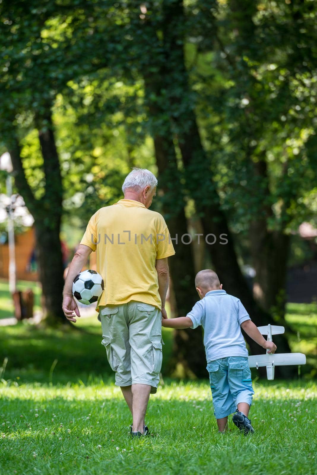 happy grandfather and child have fun and play in park on beautiful  sunny day