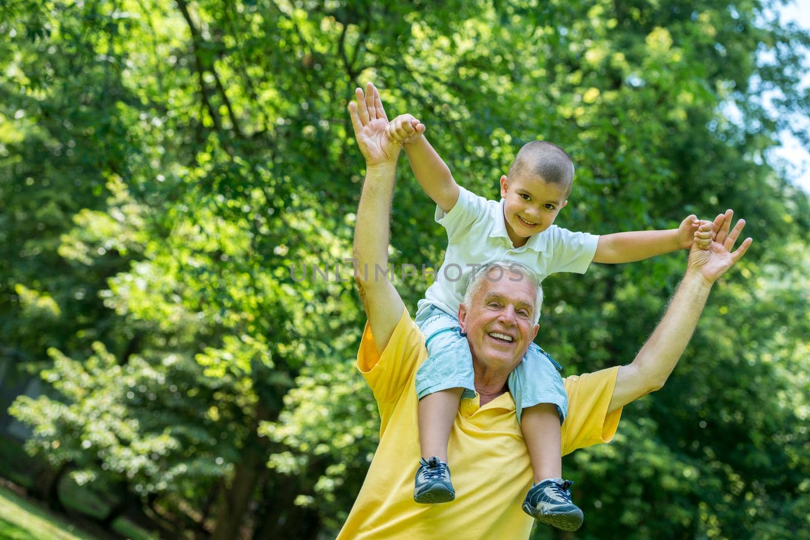 happy grandfather and child have fun and play in park on beautiful  sunny day