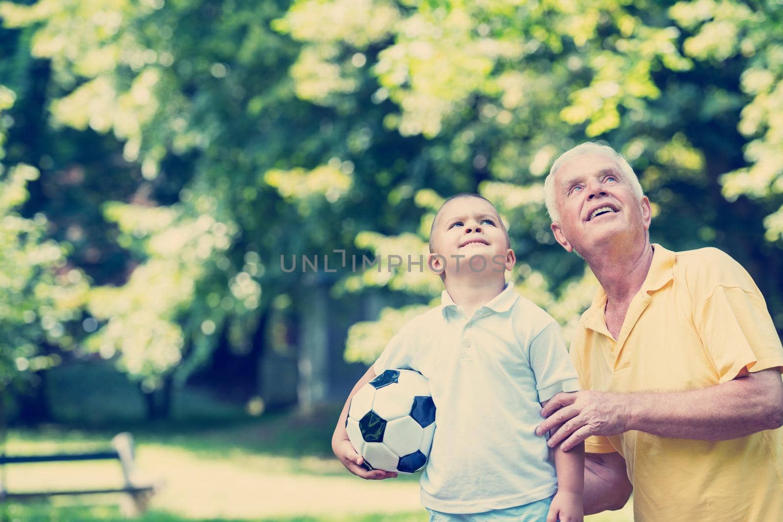 happy grandfather and child have fun and play in park on beautiful  sunny day