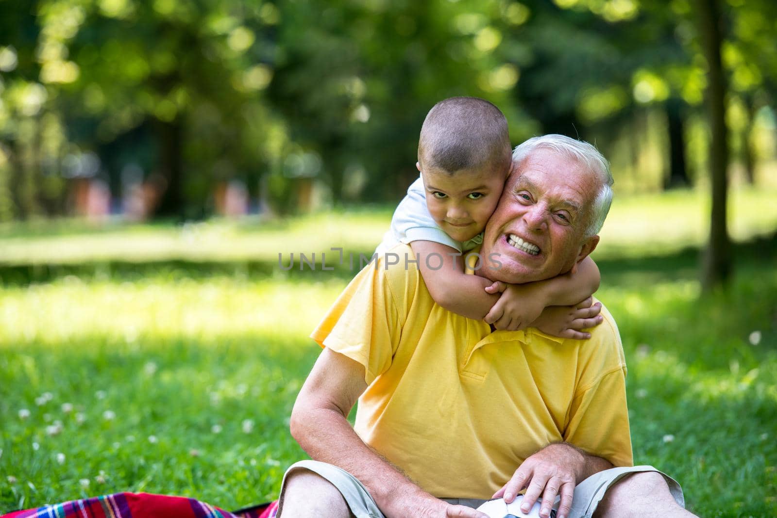 happy grandfather and child have fun and play in park on beautiful  sunny day