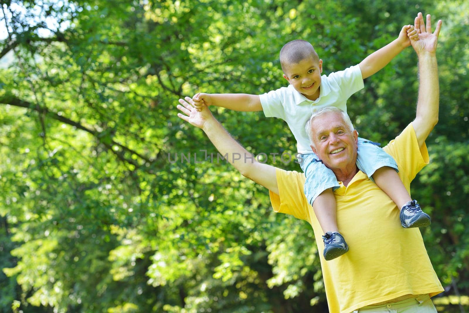 happy grandfather and child have fun and play in park